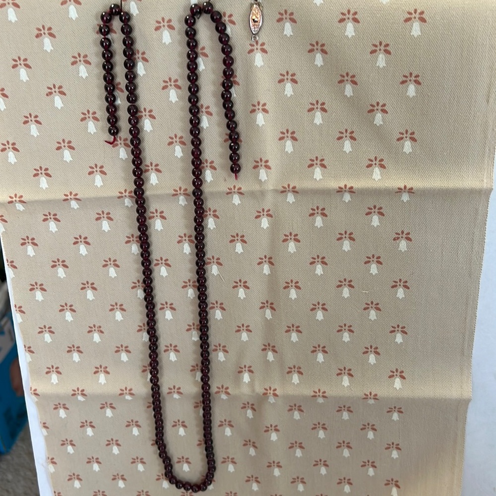 This necklace is made of garnet beads on red thread with a clasp that’s detached